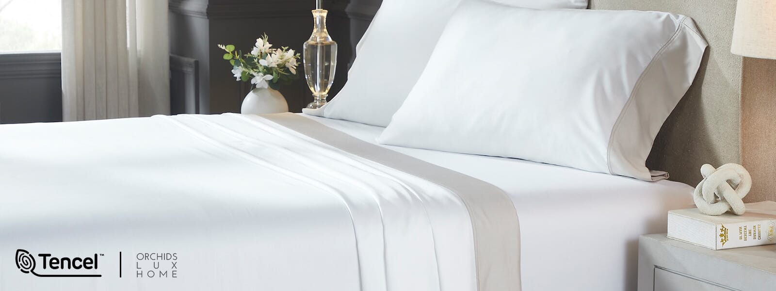Bright, minimalist bedroom with a neatly made bed dressed in crisp white sheets and pillows. Close-up highlights smooth Tencel™ bedding, conveying a clean, soft, hotel-style feel.