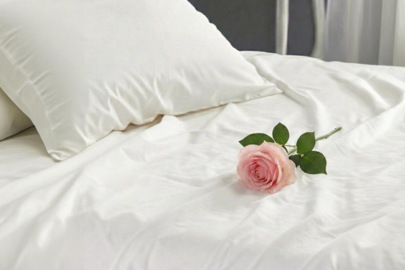 A Close-Up, Cozy Shot Of White Egyptian Cotton Sheets With A Pillow And Pink Rose.