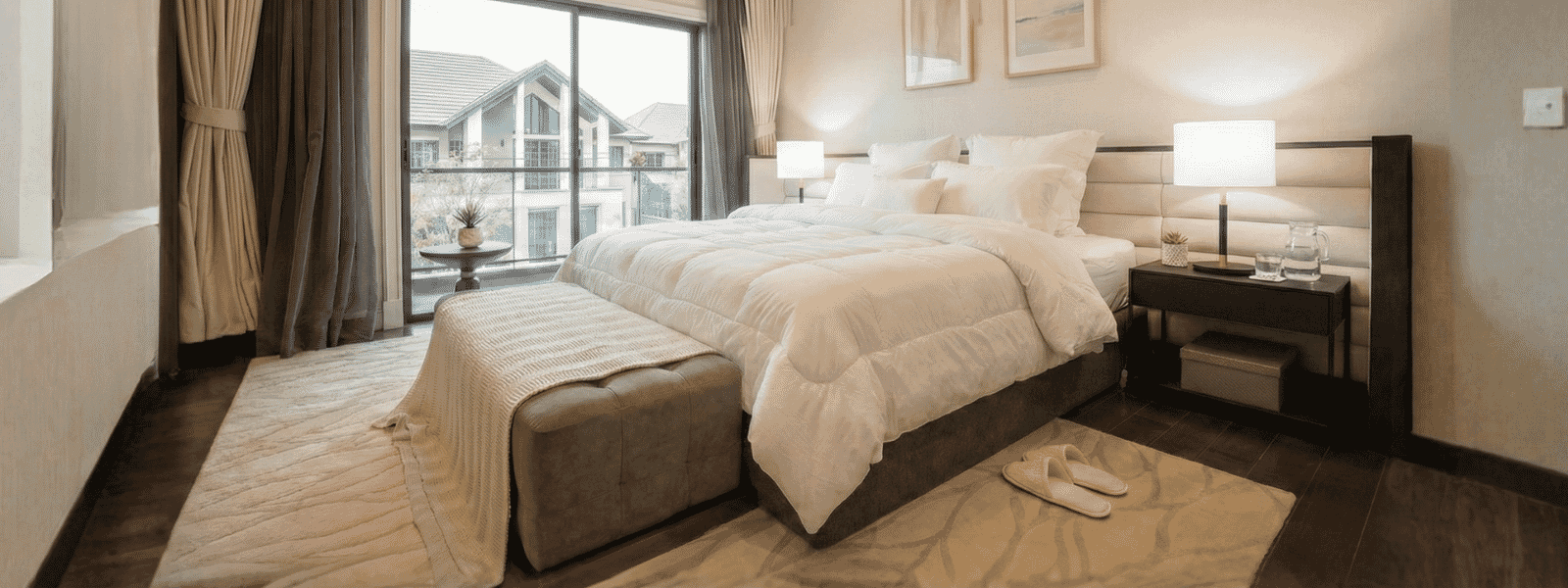 Bright Modern Guest Bedroom With Neutral Decor, King Bed, Plush Linens, And Large Window View With Curtains.